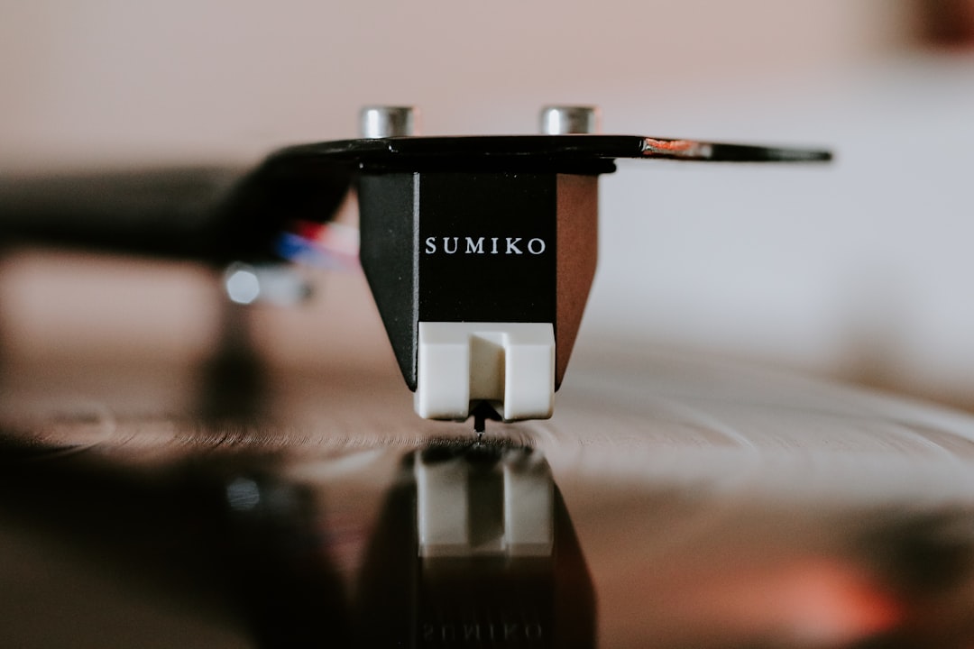 Close-up of a turntable stylus needle resting on a vinyl record groove